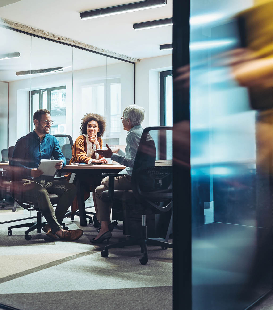 Group of business persons having a meeting in a closed glass conference room